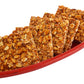 Crispy peanut and sesame chikki squares in blue box