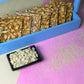 Crispy peanut and sesame chikki squares in blue box
