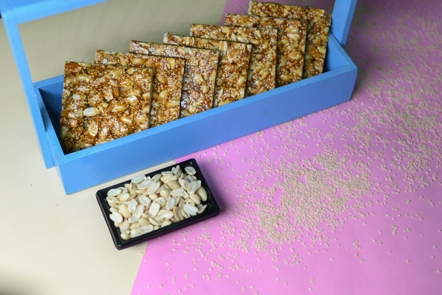 Crispy peanut and sesame chikki squares in blue box