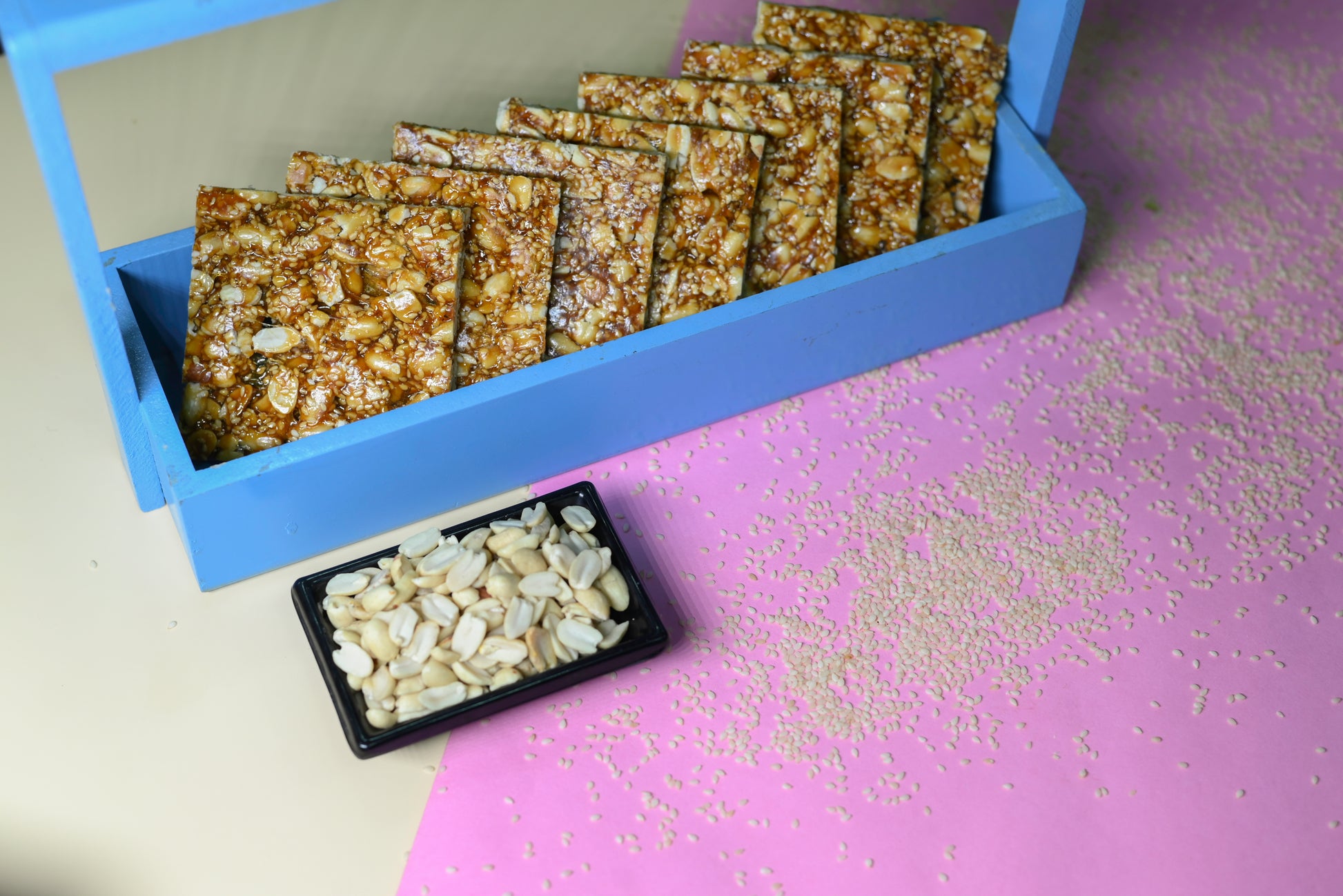 Crispy peanut and sesame chikki squares in blue box