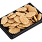 A black tray containing traditional Indian jaggery rewri, which are crunchy snack-like cakes with a nutty flavor and a textured appearance.