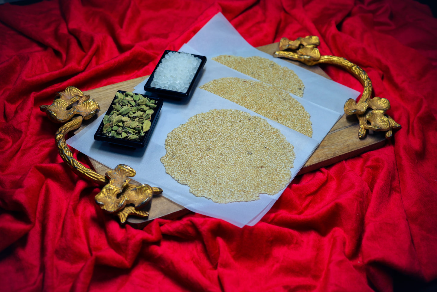 Tilpatti with cardamom and sesame displayed on red cloth background