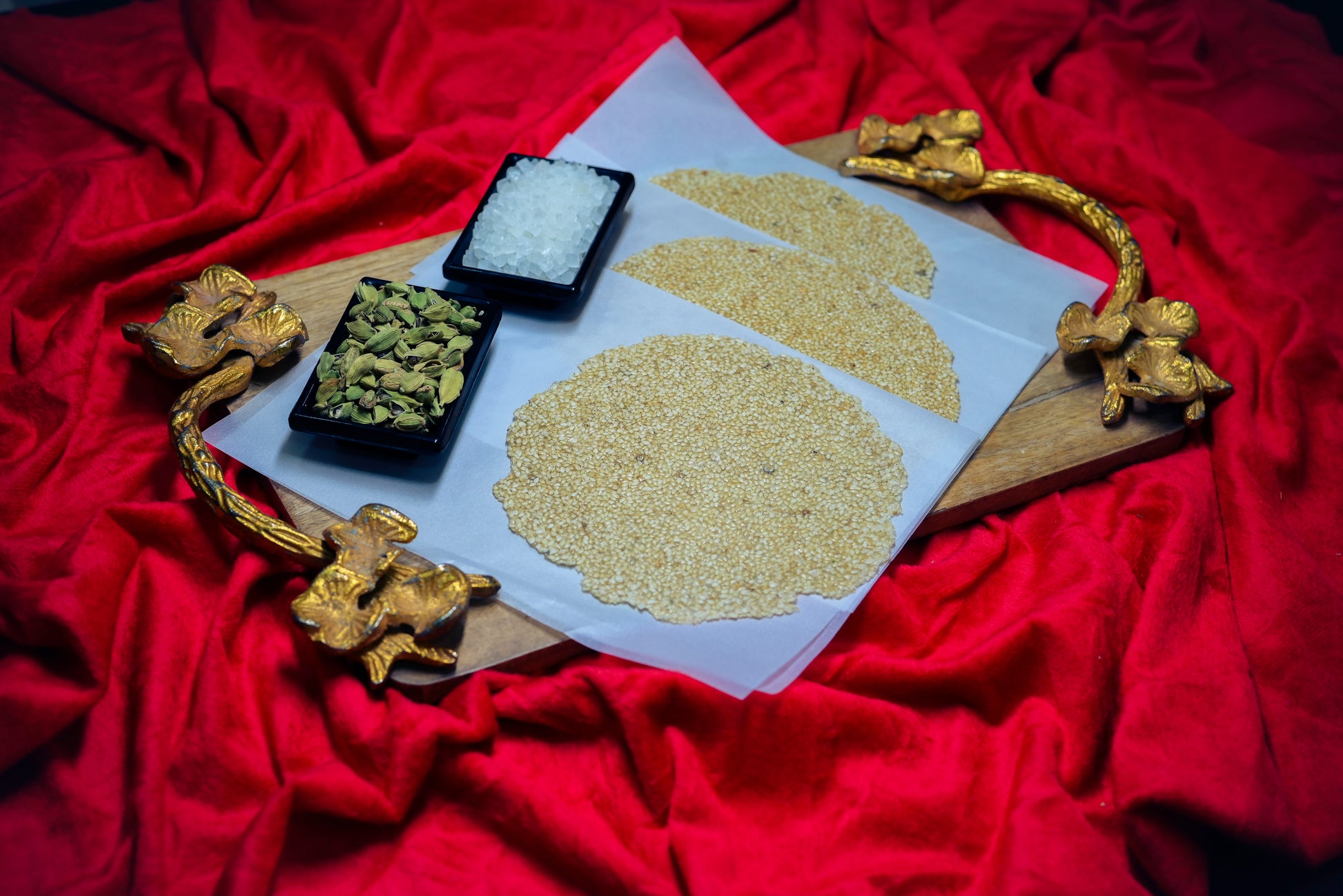 Tilpatti with cardamom and sesame displayed on red cloth background