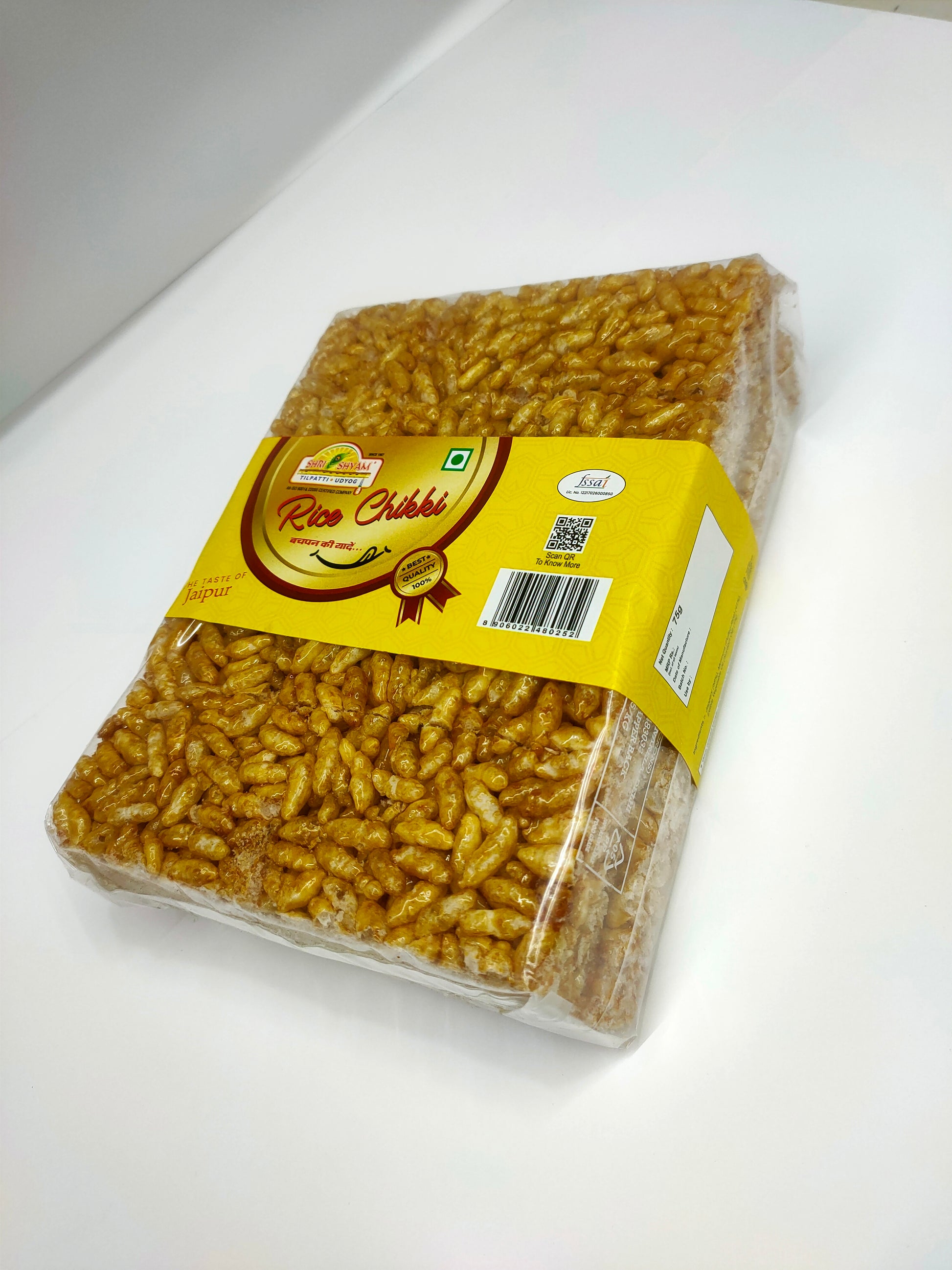 Packaged Rice Chikki snack with a yellow label on top, visible through the transparent packaging.