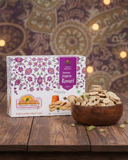Box of Rewari Jaggery with a bowl of jaggery pieces on a wooden surface.